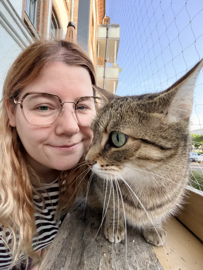 Getigerte Katze und Katzensitterin Diana am Fenster