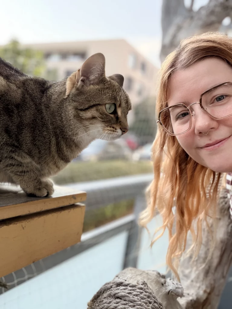 Getigerte Katze auf dem Balkon, daneben Katzensitterin Diana